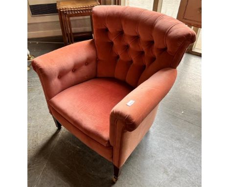 A BUTTON UPHOLSTERED ARMCHAIR  with scroll arms, on square tapering supports with brass casters