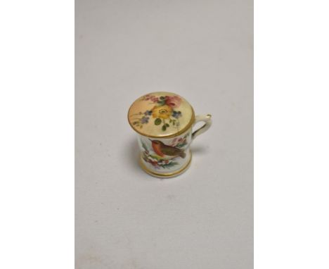 A miniature Royal Worcester hand painted cup, decorated with a robin, and a Royal Worcester blush ivory pot lid
two small hai