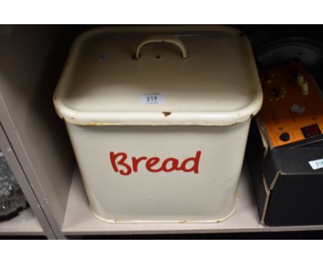 A vintage 1950s cream enamel bread bin with red writing and handles.
