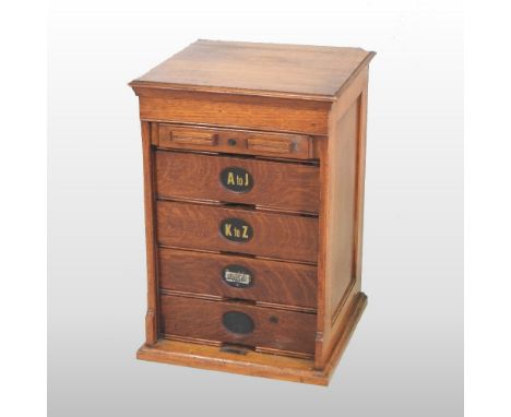 An early 20th century light oak filing cabinet, fitted with labelled drawers and enclosed by a tambour front, 40cm