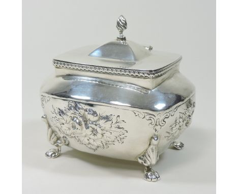 An early 20th century silver tea caddy, relief decorated with flowers, on paw feet, 11cm