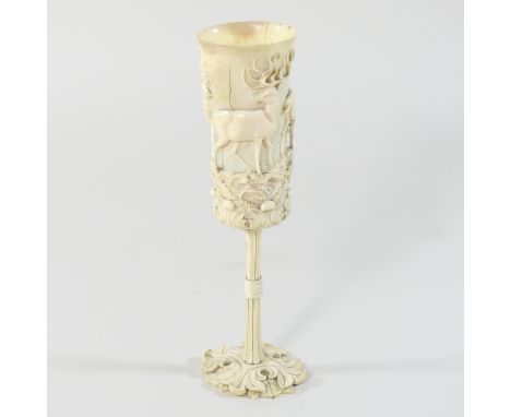 A 19th century German carved and turned ivory hunting cup, of slender form, relief carved with a frieze of stags and deer, am