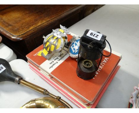 Three breakdown service grill badges, primitive lamp and a collection of motoring service manuals