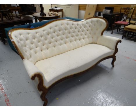 A buttoned French-style antique sofa with curved back and in cream upholstery