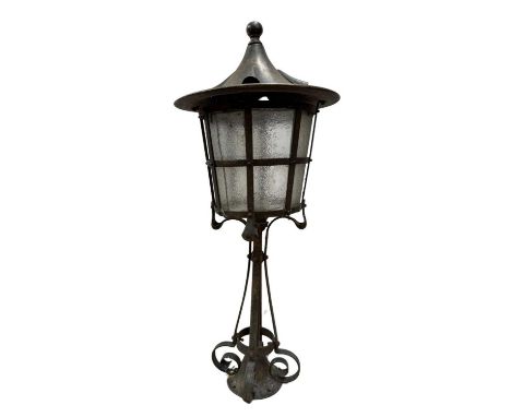 An Arts and Crafts newel post lamp, in the style of Jesson Birkett and Co., the cylindrical cage lantern with frosted glass p