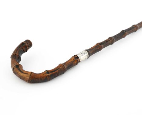 An Edwardian silver-mounted swordstick, dark stained bamboo cane in traditional form with foliate and shield engraved silver 