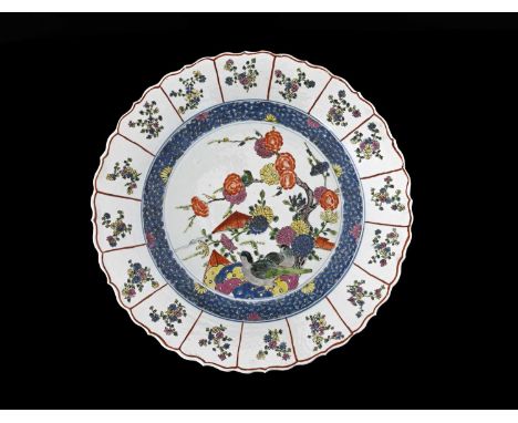A Chinese famille rose charger, Kangxi mark, ogee denticulated rim, decorated with two birds on a rocky outcrop with peony an
