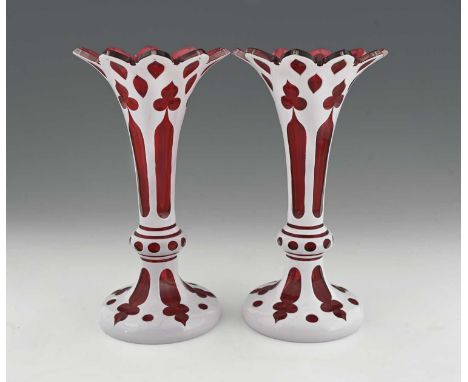 A pair of Bohemian cased glass vases, footed trumpet form, flash cut with gothic trefoil and sliced panels, opaque over red, 