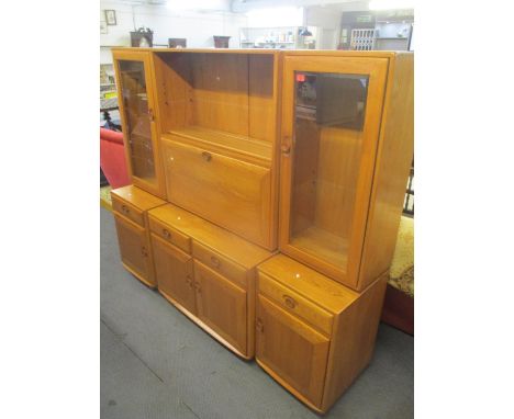 An Ercol blonde elm, three section bookcase cabinet having glazed doors flanking a fall flap above drawers and cupboards 