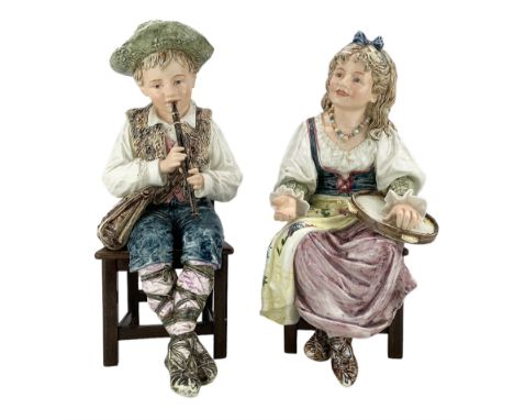 Pair of large Continental majolica musicians, modelled as a young boy and girl playing the tambourine and recorder, seated on