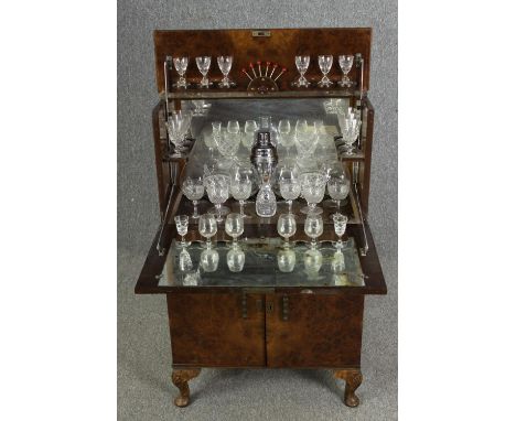 An Art Deco burr walnut cocktail cabinet, circa 1930, enclosing various cut drinking glasses and a silver plated cocktail sha