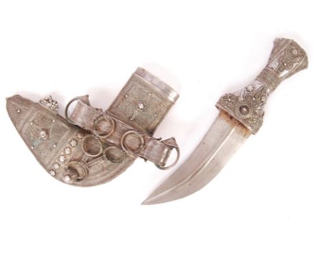 A 20th century Omani style decorative Khanjar dagger having a white metal thread decorated waisted handle and a curved ridged