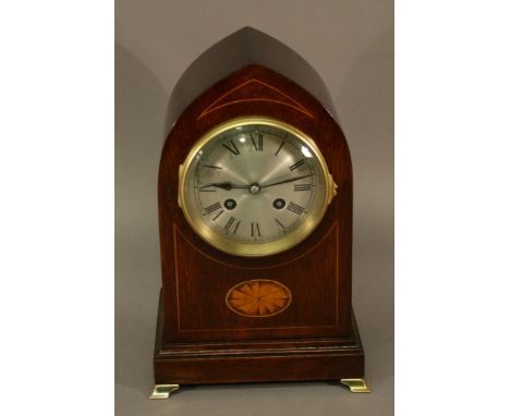 AN EDWARDIAN MAHOGANY EIGHT-DAY MANTEL CLOCK the case having a pointed arch shape and inlaid oval paterae, the circular silve
