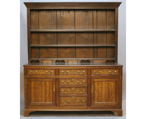 A GEORGE III OAK DRESSER AND RACK having a moulded cornice and three shelves with shaped base supports, the lower stage havin
