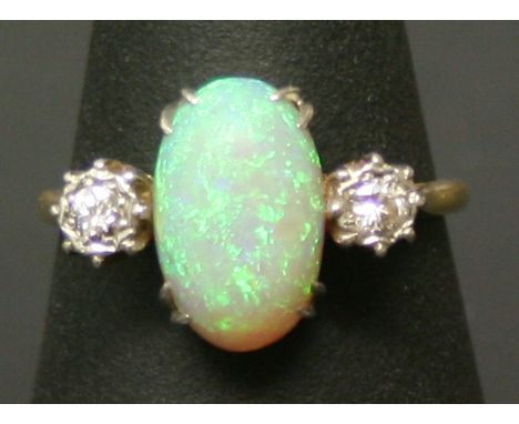 A GOOD YELLOW METAL AND DIAMOND RING the large oval opal cabochon flanked by illusion-set diamonds, rubbed marks testing as g