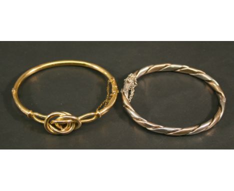 A 9CT GOLD BANGLE of knotted design, marked 9c. 6.5cm, 7grams; sold together with a white and yellow metal bangle of twisted 