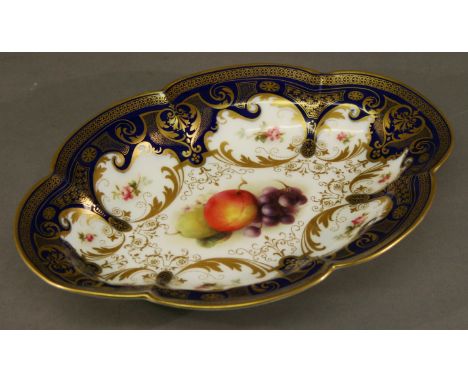 A ROYAL WORCESTER HAND-DECORATED DISH of lobed oval form, the centre painted with fruit in a band of foliate vignettes and gi