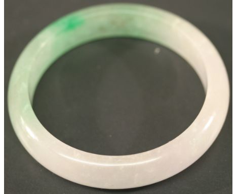 A CARVED CHINESE JADEITE BANGLE of circular form with translucent green to white colouring. 7cm(d) CONDITION: Generally good