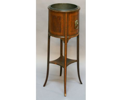 AN EDWARDIAN MAHOGANY PLANTER of cylindrical form with metal liner, crossbanded panels, lion mask and ring handles, raised on