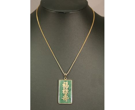 A CHINESE STYLE YELLOW METAL MOUNTED JADE PENDANT of oblong form with Chinese characters, suspended by a fine linked chain ma