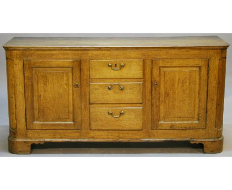 A GEORGE III OAK DRESSER BASE of oblong form with rounded front corners above three central drawers flanked by fielded panel 