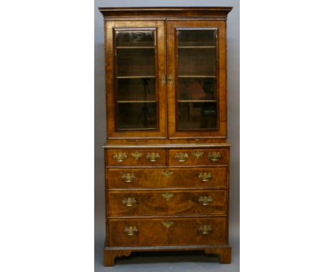 A GEORGE I WALNUT BOOKCASE OVER CHEST having a moulded cornice, two oblong glazed doors and candle slides, the lower stage ha