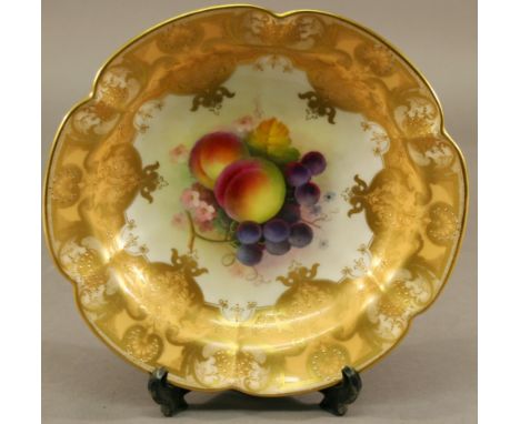 A ROYAL WORCESTER HAND-DECORATED DISH of lobed, dished circular form, the interior painted with fruit in a gilt decorated ora