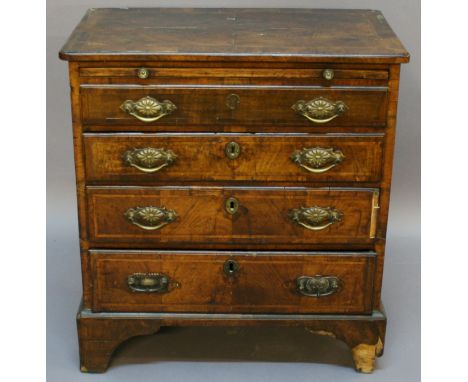 AN 18TH CENTURY WALNUT BATCHELORS' CHEST having a feather banded and quarter veneered top with re-entrant front corners above