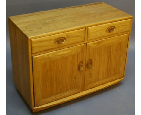 A SMALL ERCOL LIGHT ELM SIDEBOARD constructed with visible dove-tail joints to the top, having two drawers over two piano-hin