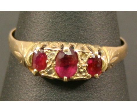 AN 18CT GOLD AND RUBY THREE STONE RING, the three oval-cut rubies interspersed by small diamond chips, marked 18, ring size U