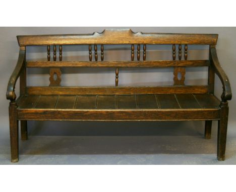 A 19TH CENTURY OAK HALL BENCH having a triple railed back with spindle and splat supports, planked seat and down-swept open a