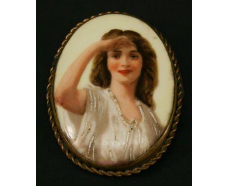 AN OVAL PORCELAIN PORTRAIT PLAQUE BROOCH painted with a young female, in a gilt metal rope-twist surround, the plaque with mo