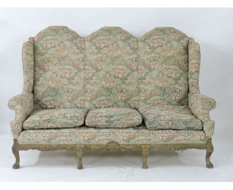 A George II style settee, with a carved show frame, three camel backs, the base carved with shells and 'C' and 'S' scrolls, 1