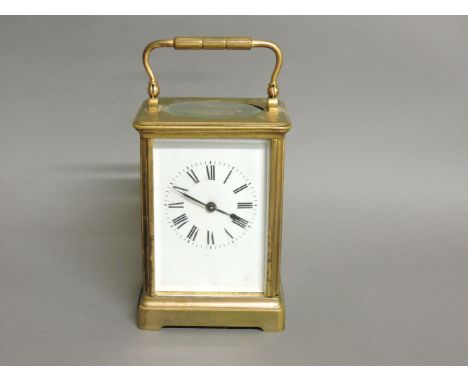 A French brass carriage clock, with white enamel dial, striking the half hours on a gong, 18cm to top of handle