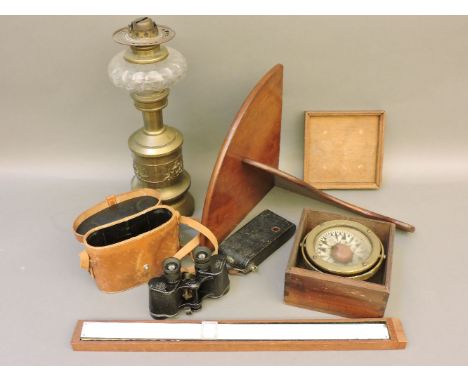 A pair of Carl Zeiss binoculars, a rule, a camera, a boxed compass on a gimballed bracket, a brass and glass oil lamp, and a 