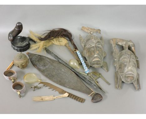 A collection of tribal items, an aboriginal thrower, two masks, two fly swats, a penis carved cigarette ashtray, two beadwork