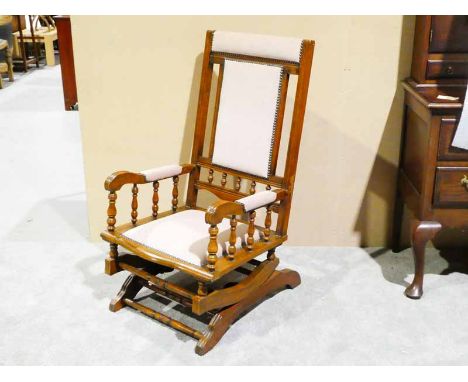 An early 20th century American Bobbin Rocking Chair with upholstered back and seat, turned bobbin supports to arms and back 