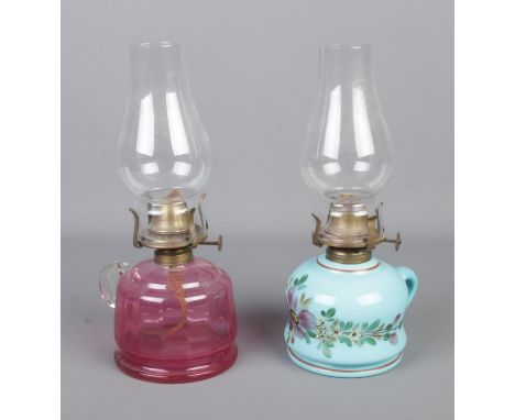 Two small oil lamps to include cranberry glass and blue glaze, hand painted ceramic example.  Nibbles to glass funnel and aro