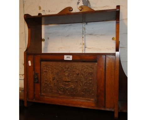 An Edwardian oak hanging shelf with carved panelled door.