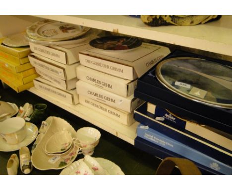 A shelf of boxed Collector's plates including Brothers Grimm Fairy Tales, Concorde plate and Belleek boxed plates.