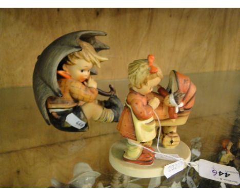 A large Goebel's Hummel boy under an umbrella and a smaller Hummel girl with a dolls pram.