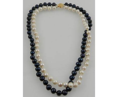 In the style of Chanel, an unusual double strand black and white pearl necklace, with 14 carat yellow gold clasp. 