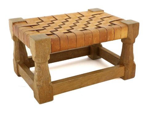 Workshop of Robert Mouseman Thompson (Kilburn): An English Oak Footstool, woven leather top, on four octagonal legs joined by