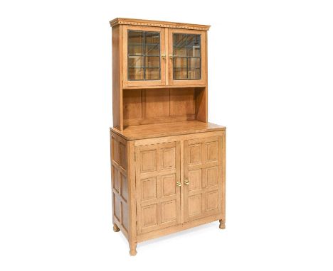 Yorkshire School: An Oak Panelled Display Cupboard, the top section with two leaded glazed doors enclosing two glass shelves,