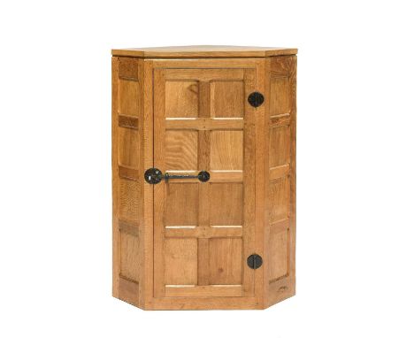 Workshop of Robert Mouseman Thompson (Kilburn): An English Oak Hanging Corner Cupboard, with panelled door enclosing three fi