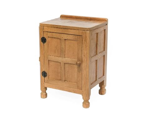 Workshop of Robert Mouseman Thompson (Kilburn): An English Oak Panelled Bedside Cupboard, with raised upstand, above a door, 