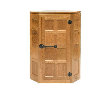 Workshop of Robert Mouseman Thompson (Kilburn): An English Oak Panelled Hanging Corner Cupboard, with panelled door enclosing