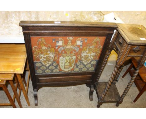 An oak framed and needlework firescreen depicting a crest 