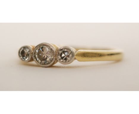 A mid 20th Century 18ct diamond three stone ring millegrain set stones to knife edged shoulders, ring size K. 