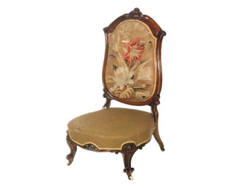 A Victorian mahogany framed prie dieu or prayer chair, with a foliate carved top crest and acanthus scroll front legs, with a